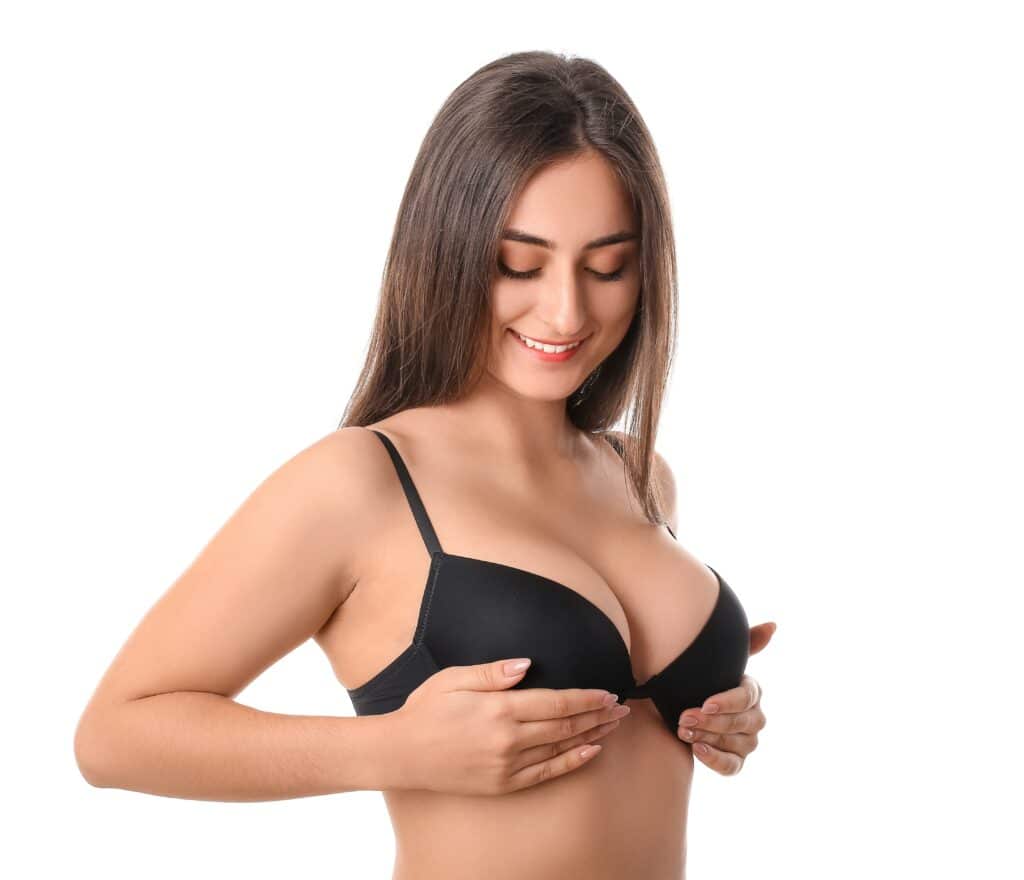 Woman in black bra smiling and feeling her natural breast augmentation with fat transfer in Orange County, CA