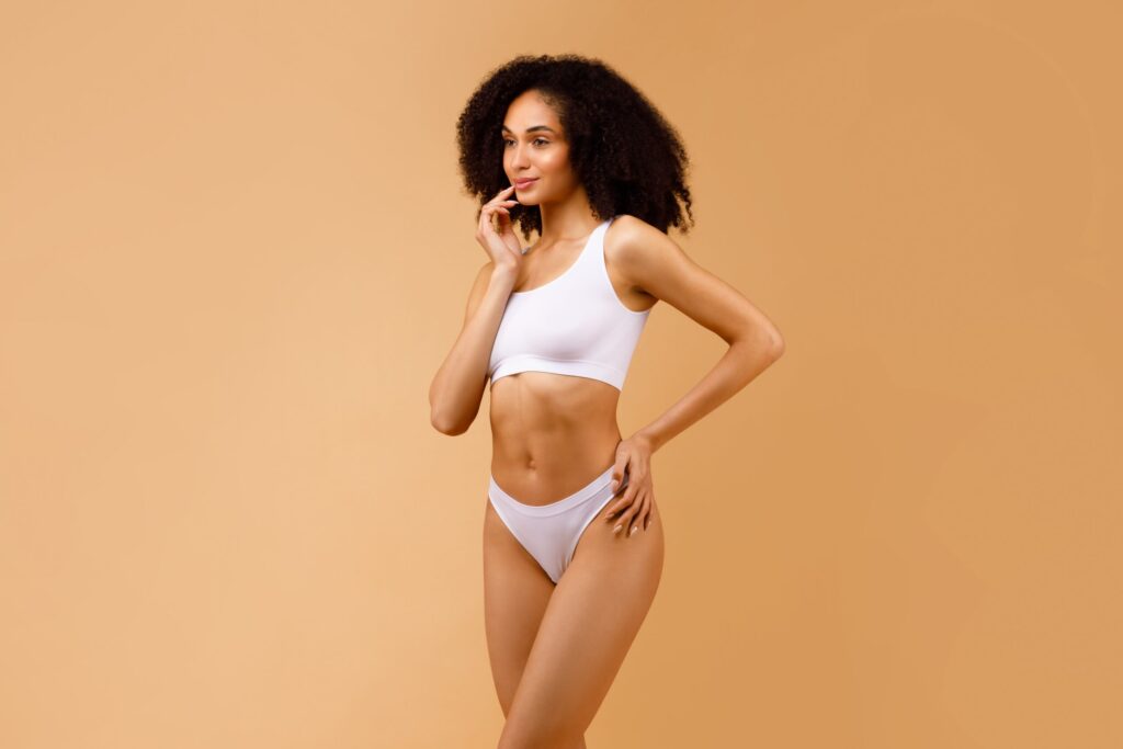A woman posing in white underwear showing the results of liposuction in Orange County