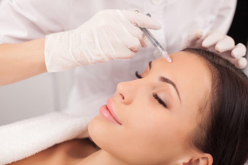 Relaxed woman receiving Dysport injections in her forehead.