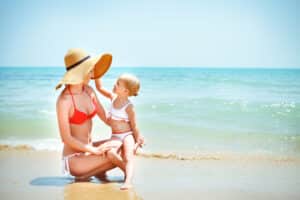 Mom in bikini on the beach after mommy makeover in Huntington Beach, CA
